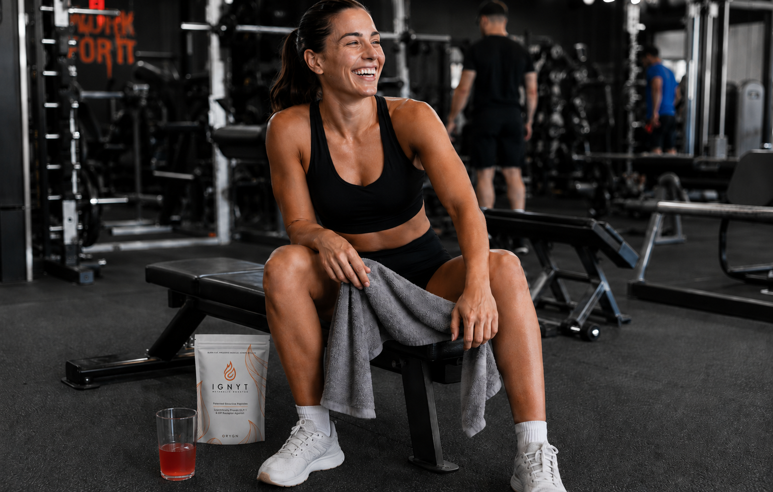 Woman in the gym sitting next to an IGNYT bag and a glass